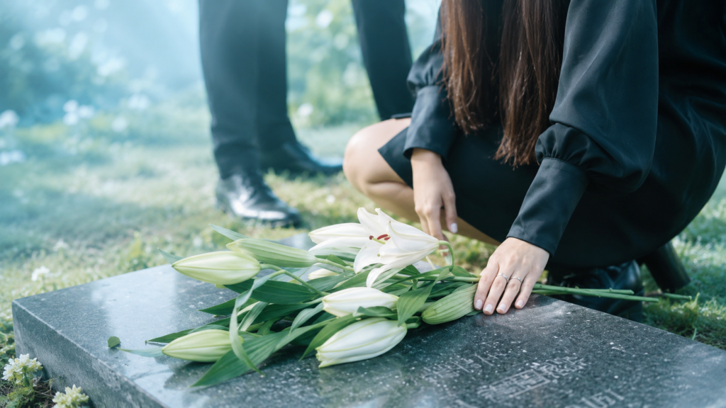 Family member placing white lilies at a graveside during a funeral service